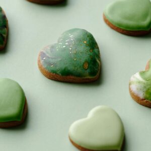 Assorted heart-shaped cookies with green icing on a pastel background, perfect for a sweet treat.
