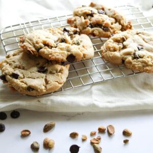 Close-up of freshly baked chocolate chip cookies on a cooling rack with scattered nuts.