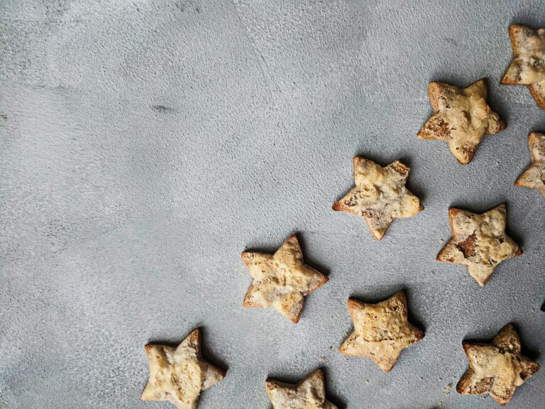 Star-shaped homemade cookies scattered on a textured gray surface, perfect for festive occasions.